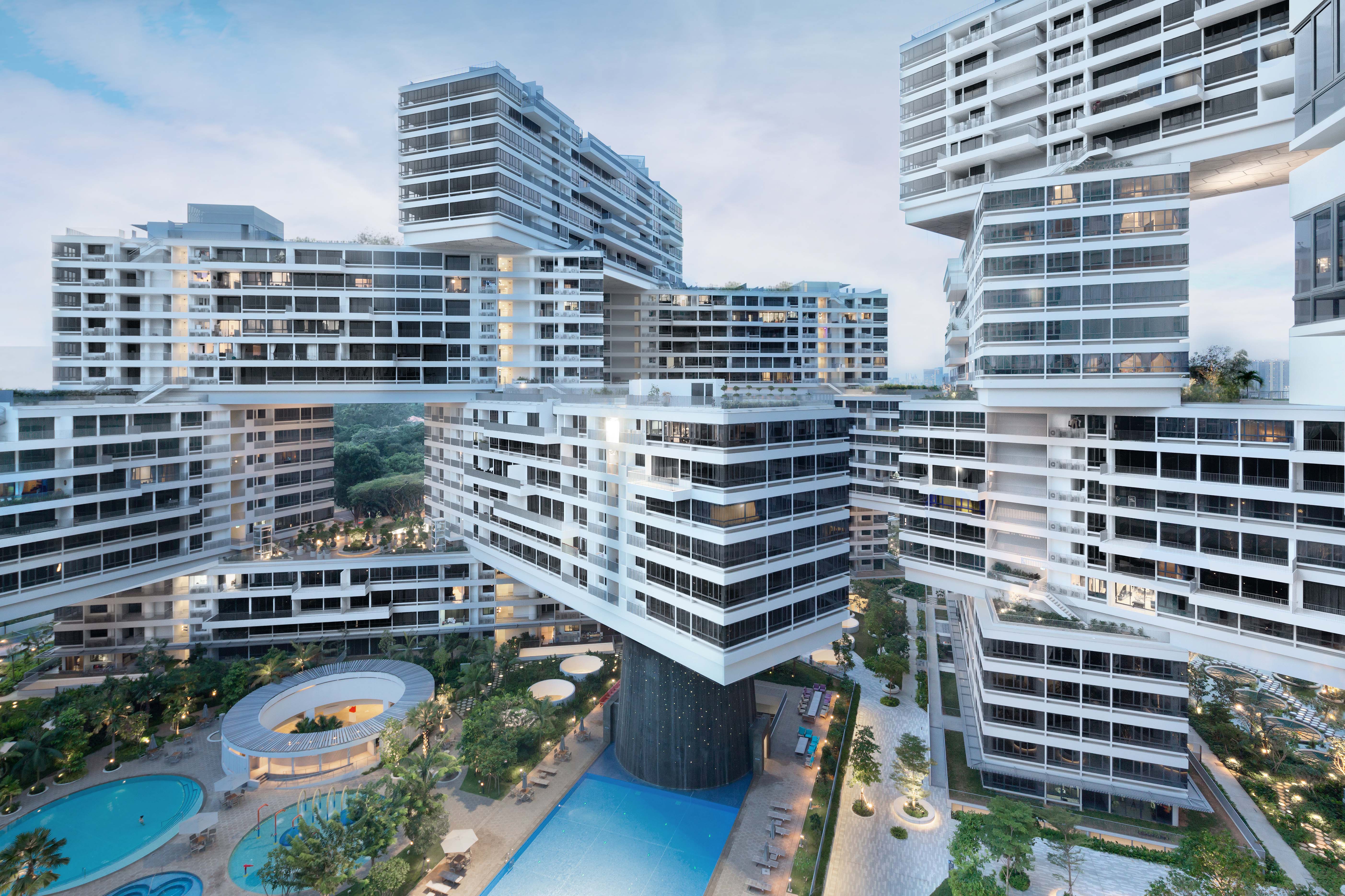 A large, modern and complex building runs through the picture. At the bottom of the picture is a courtyard with pool facilities and lawn. Behind it rises the multi-storey building. It consists of many winding blocks.