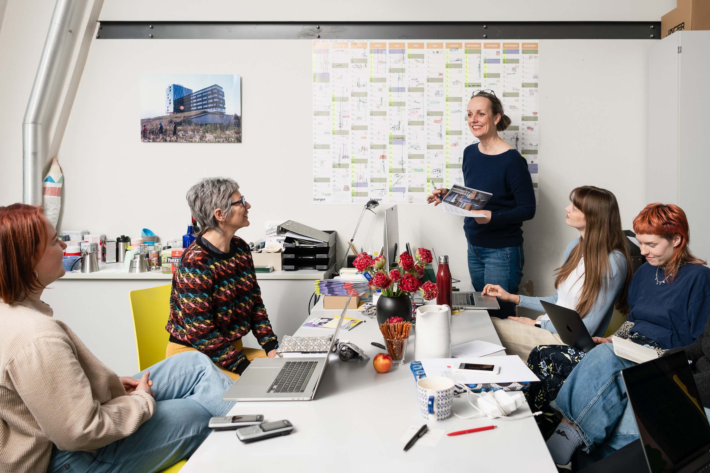 Fünf Personen mit Laptops in einem Beschprechungsraum.