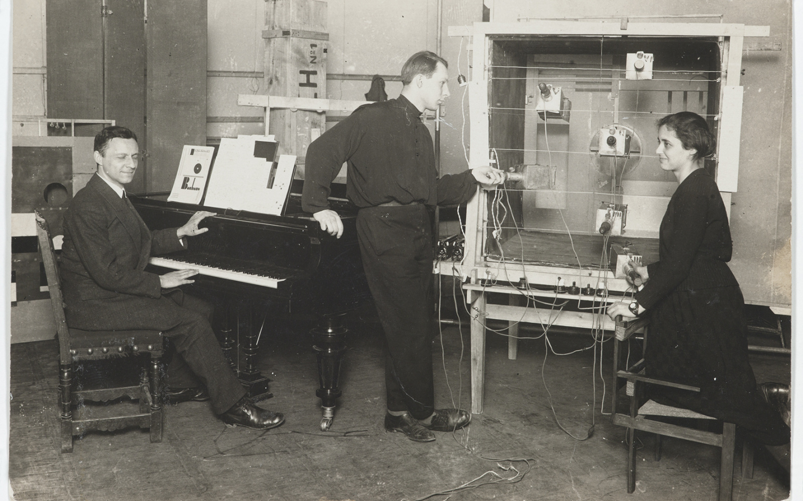 Ludwig Hirschfeld-Mack (l. am Klavier), Theo Bogler (m.), Marli Heiman (r.) an der Apparatur, bei der Aufführung von Kreuzspiel, um 1924