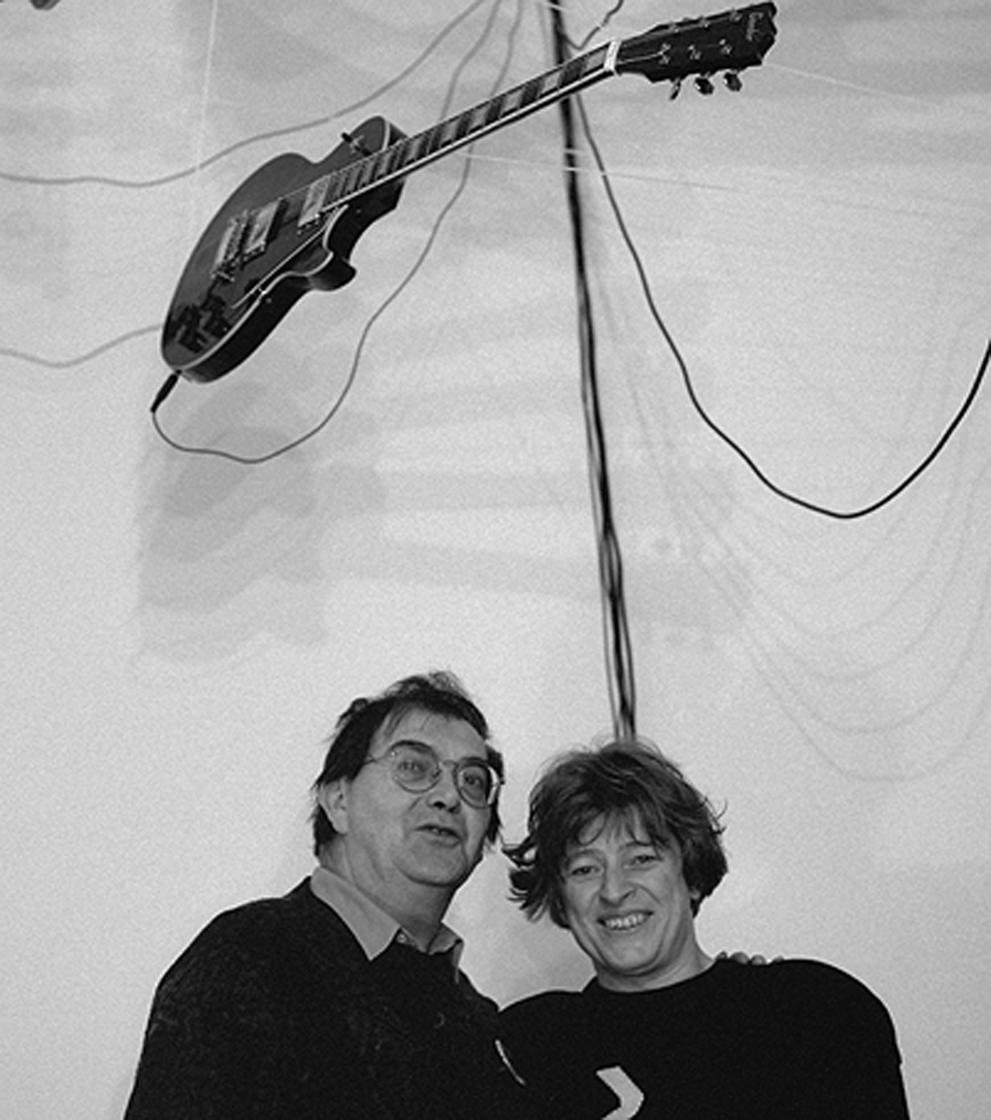 B / W photography. About two people hanging on a electric guitar.