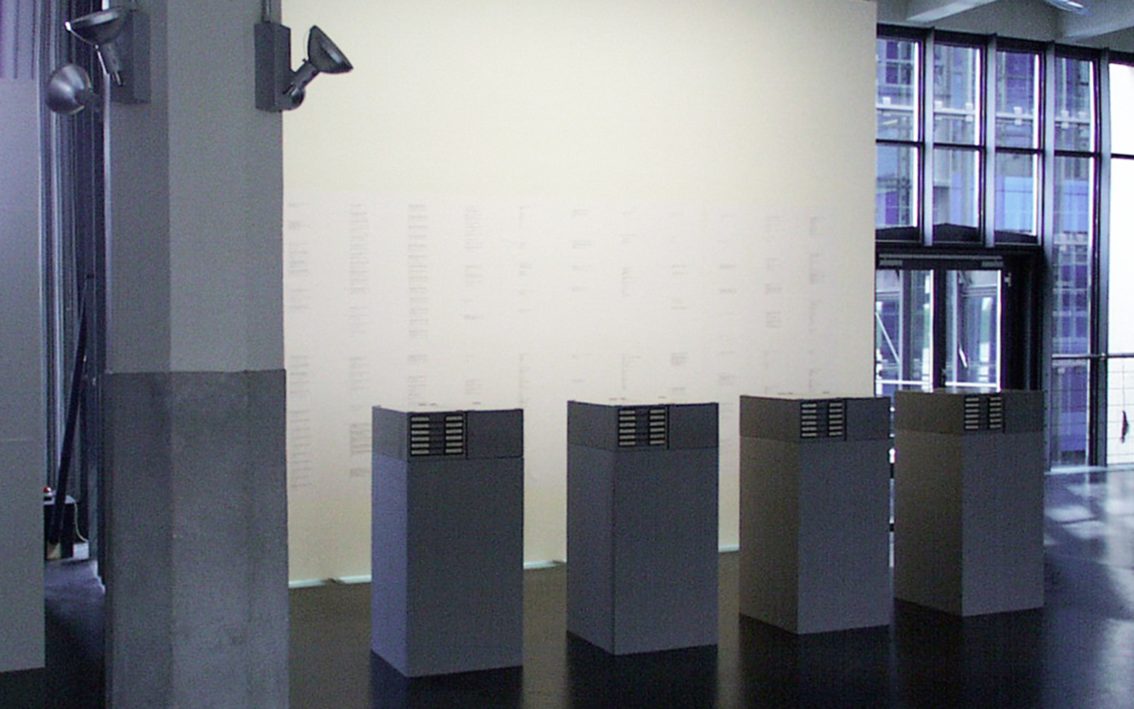 Four gray filing cabinets in front of a brightly lit wall.