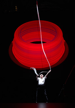 A man handle a huge red ring in front of a black background