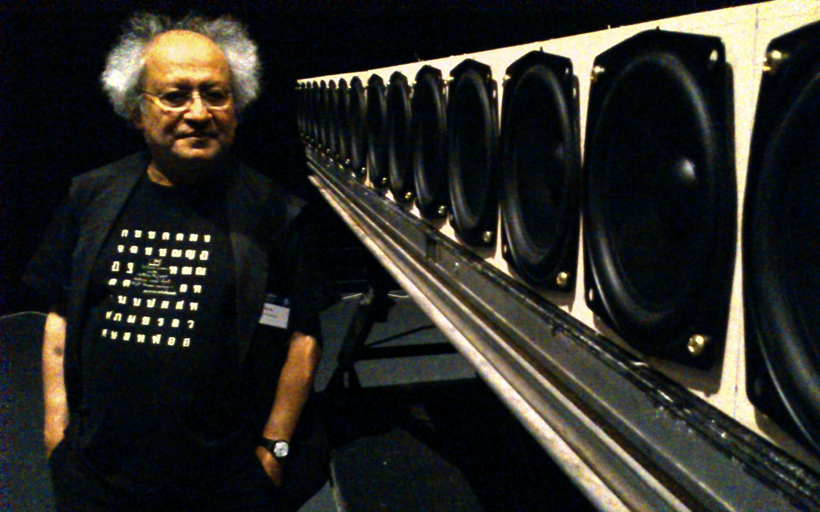 A man stands next to a set of speakers