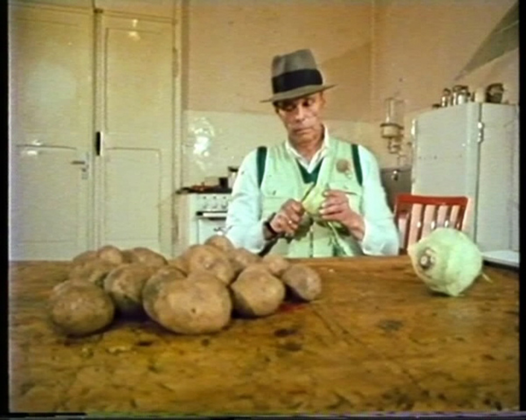A man sitting at a table and peels potatoes and turnips