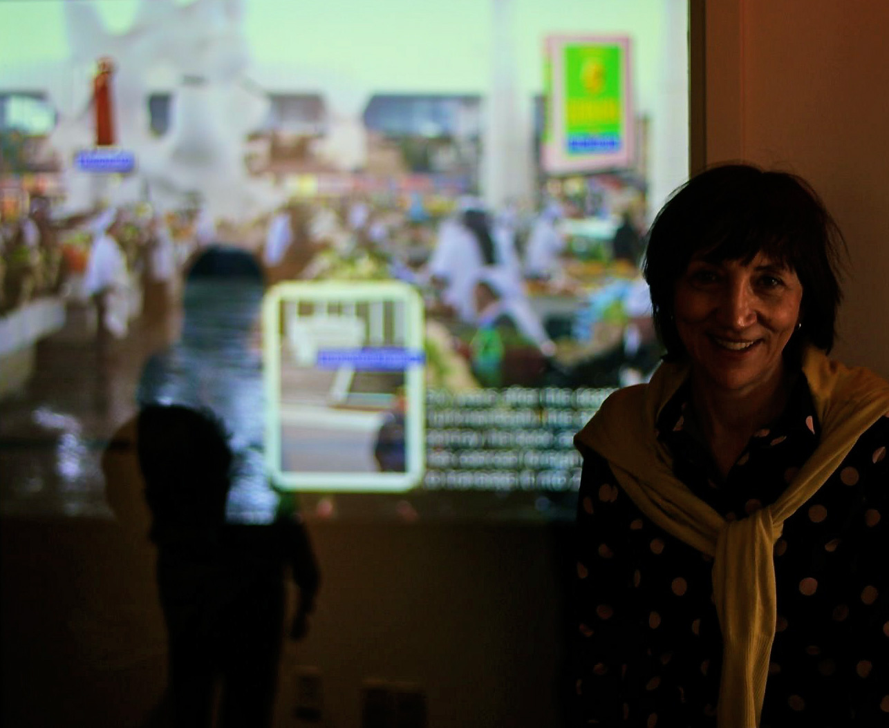 A woman standing in front of a canvas which shows a desktop with open programs