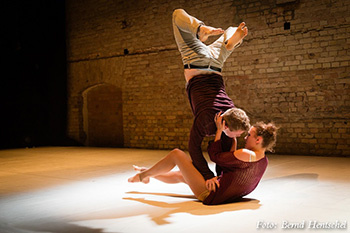 A dancing couple on stage. While this makes on her hips a handstand, she tries to kiss him.