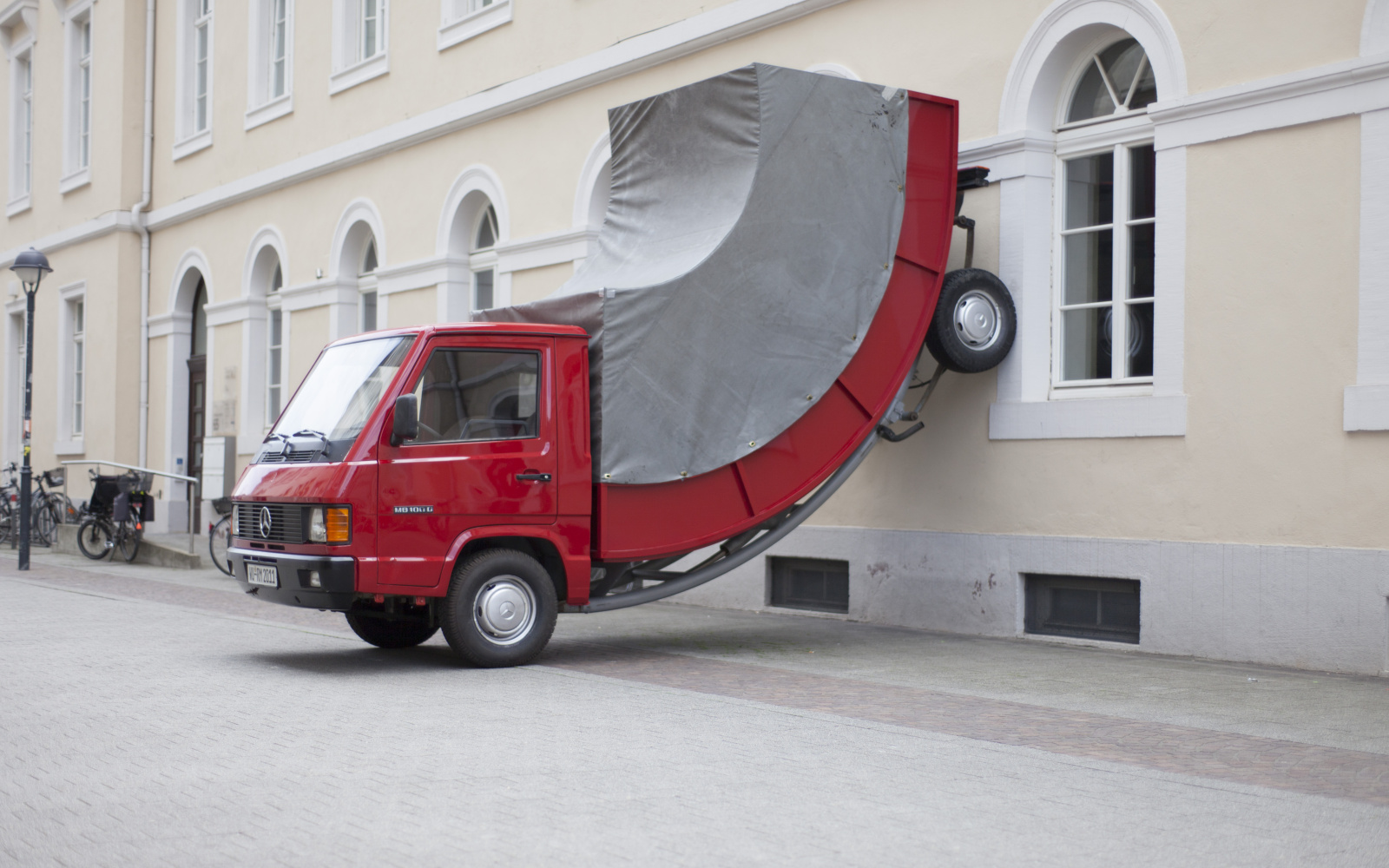 A red truck whose rear wheels stand at the wall
