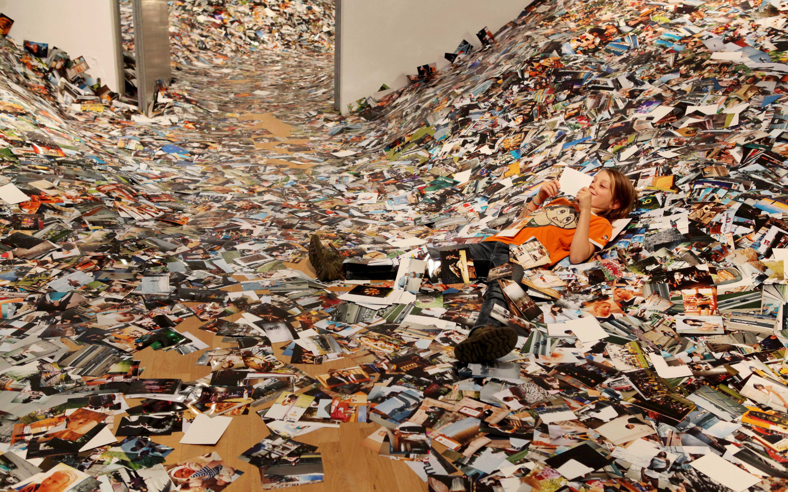 A boy lying in a pile of photographs