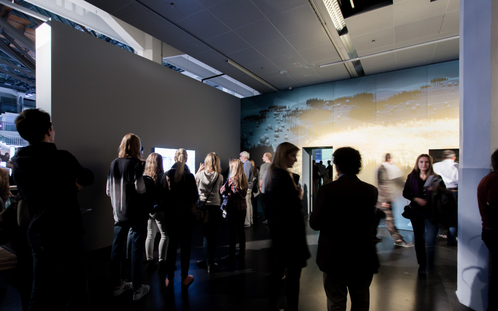 Many people standing in a room, looking at the artworks