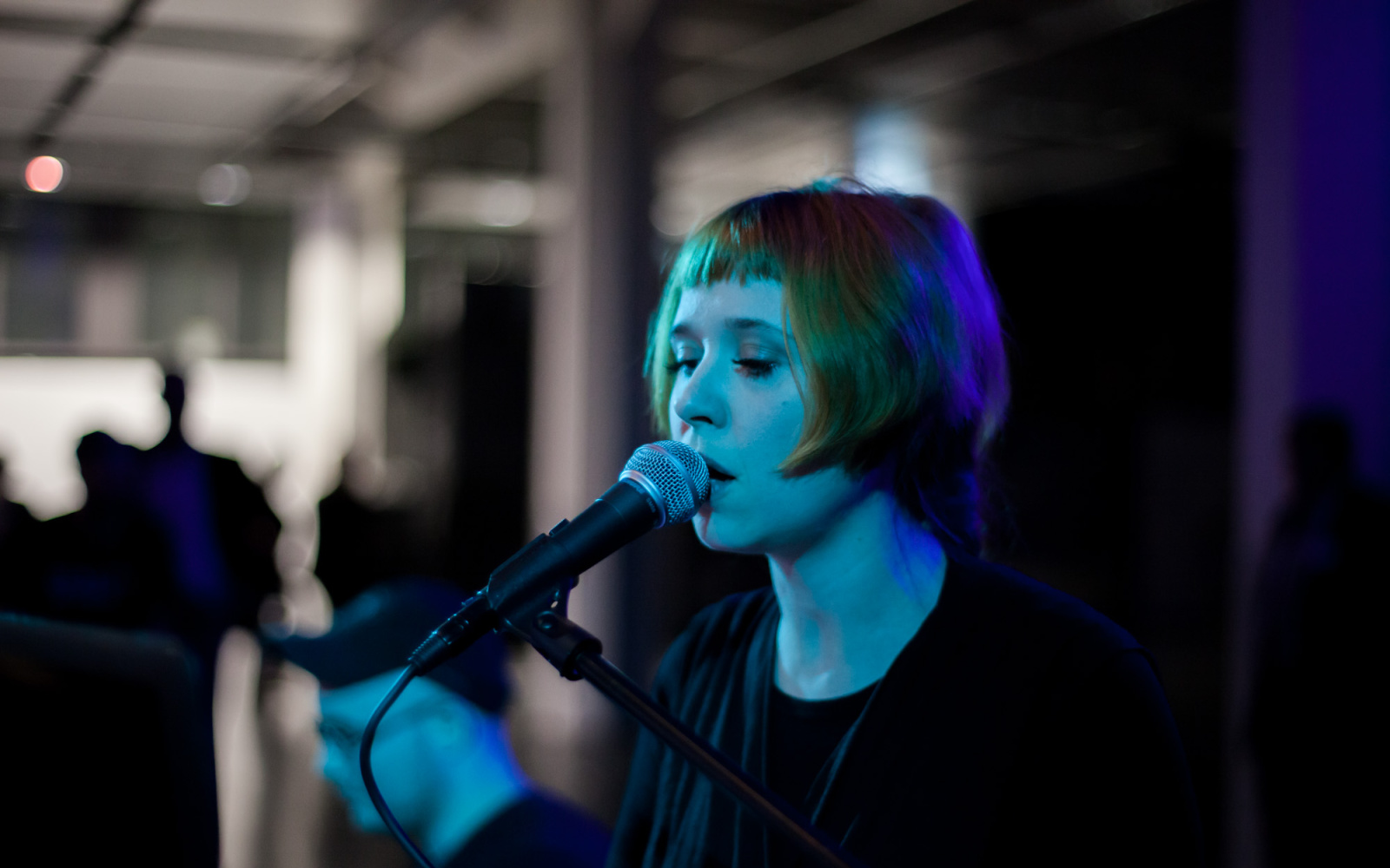 Singing woman at a microphone. The scene is lit by blue lights.