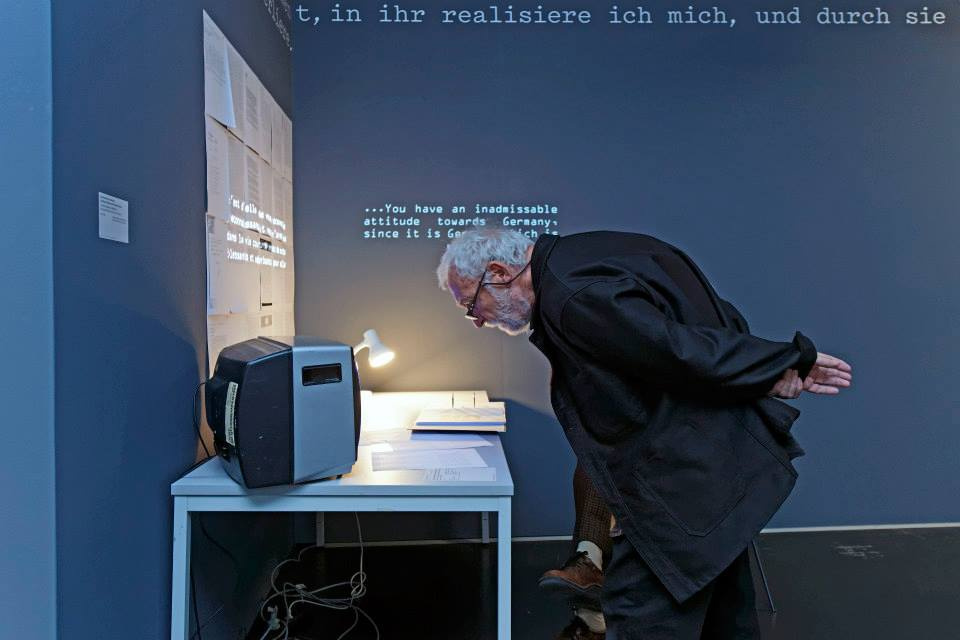 A man reading in front of a small screen the description