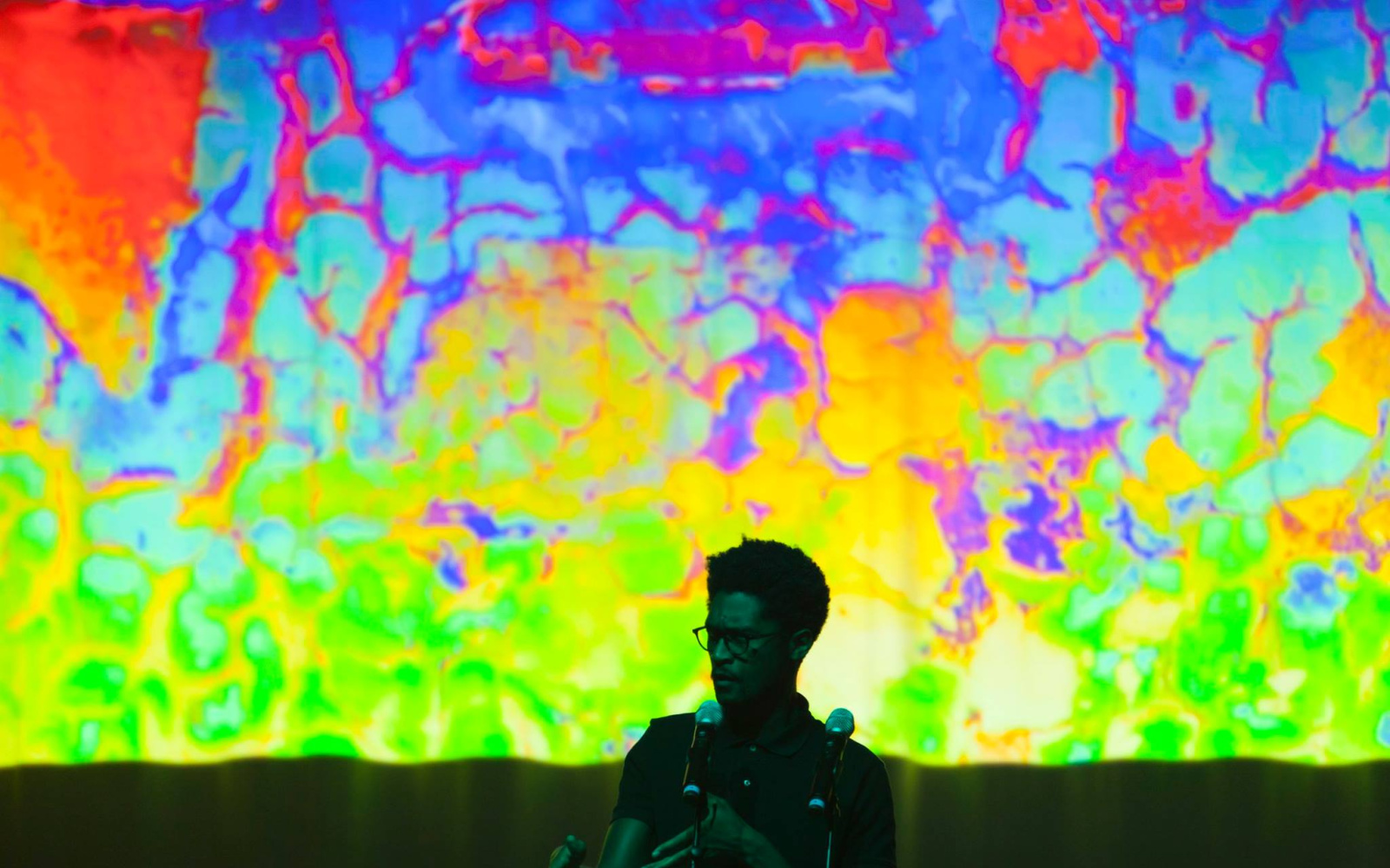 A man stands in front of a colorful screen