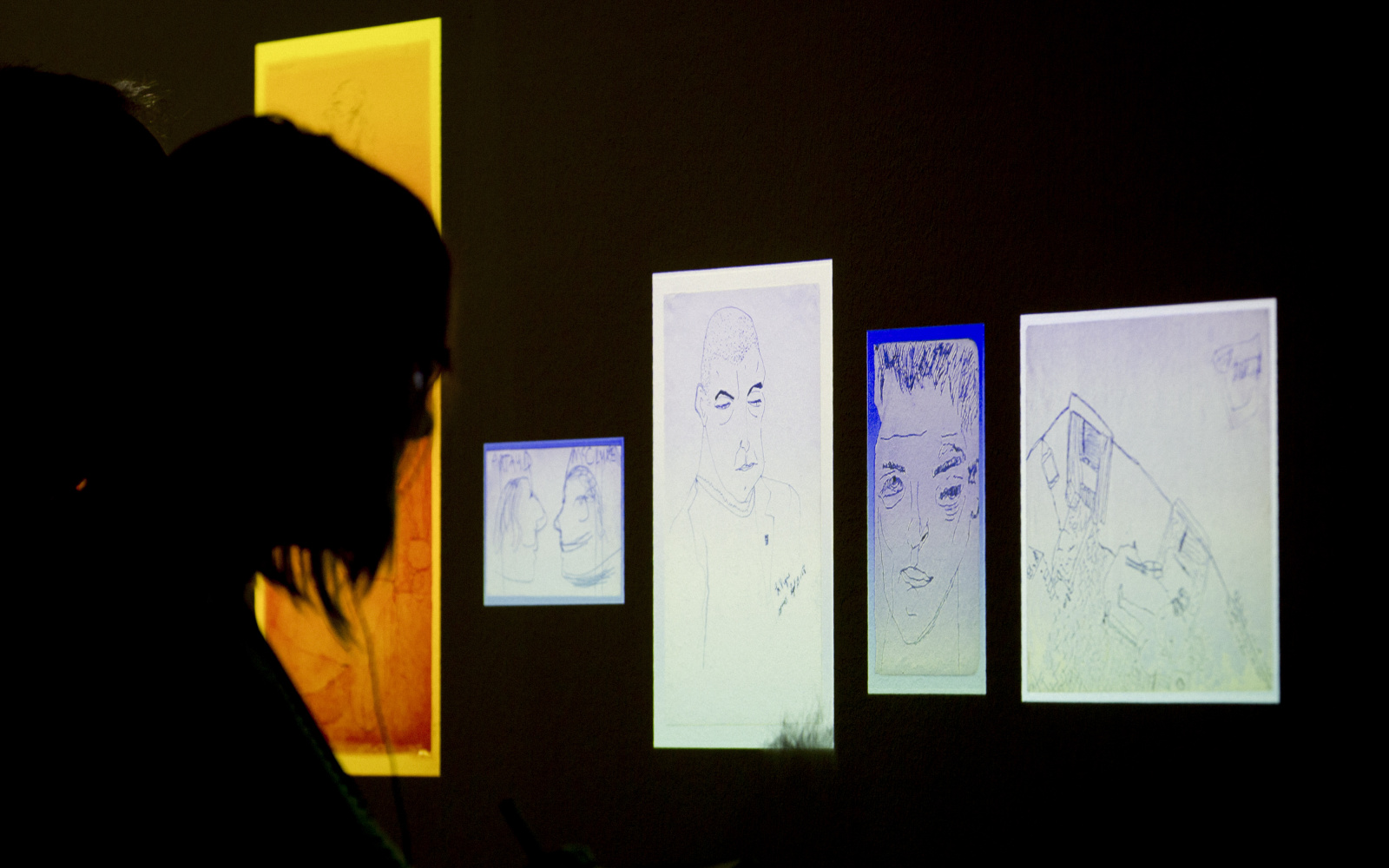 Eine Person blickt im Dunkeln auf beleuchtete Zeichnungen