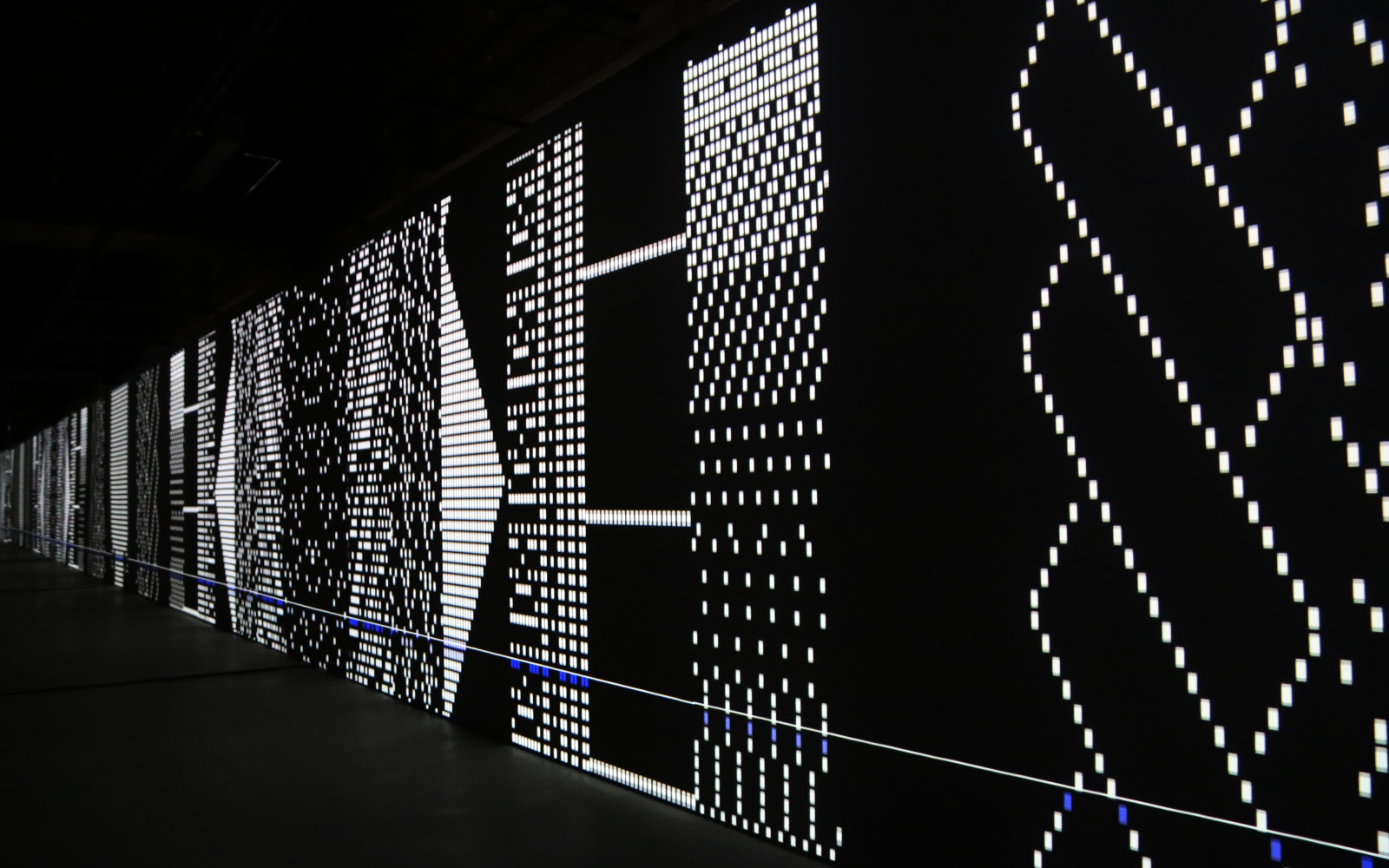 Lichtprojektion auf länglicher Leinwand in schwarzem Raum.