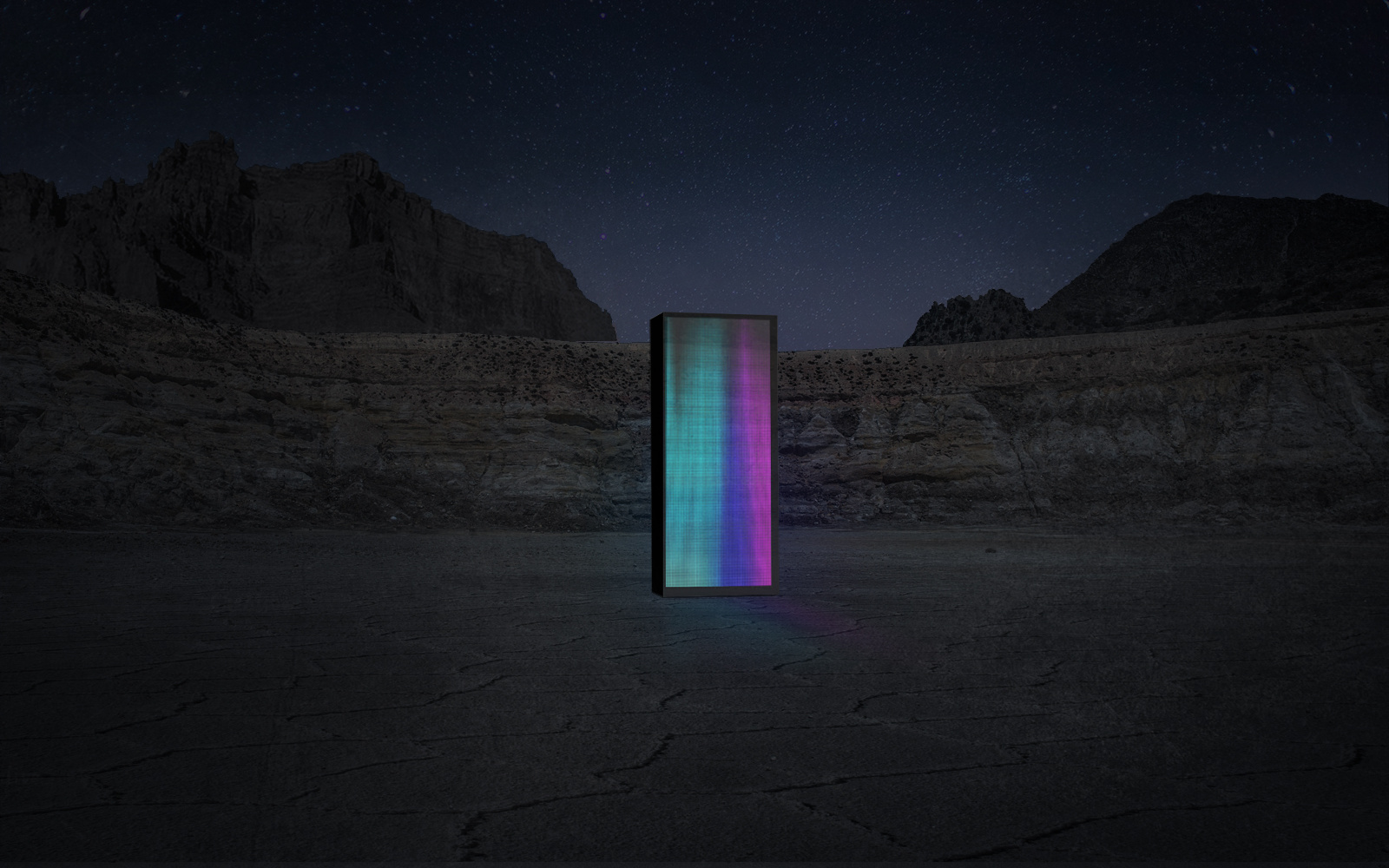 Colorful illuminated LED sculpture in the wild under starry sky.