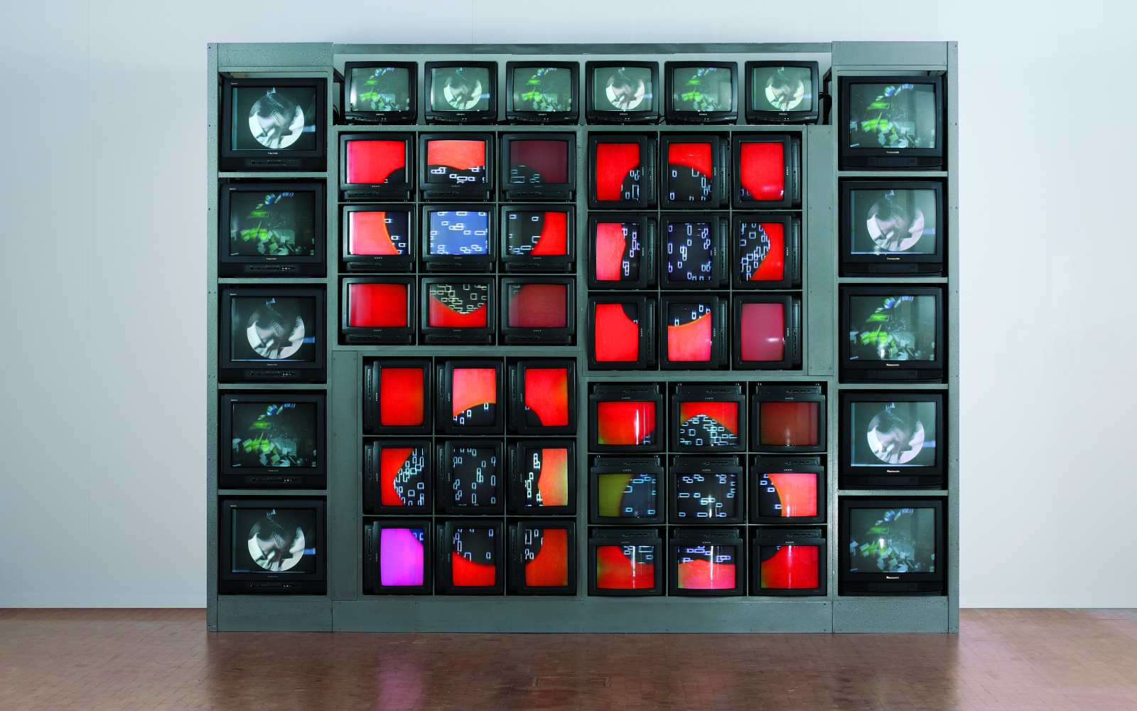 Skulptur aus verschieden großen Fernsehapparaten die mit unterschiedlichen Videos in kräftigen Farben bespielt werden.