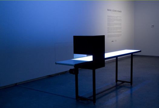 Illuminated tabletop with attached box in bluish-lit room.