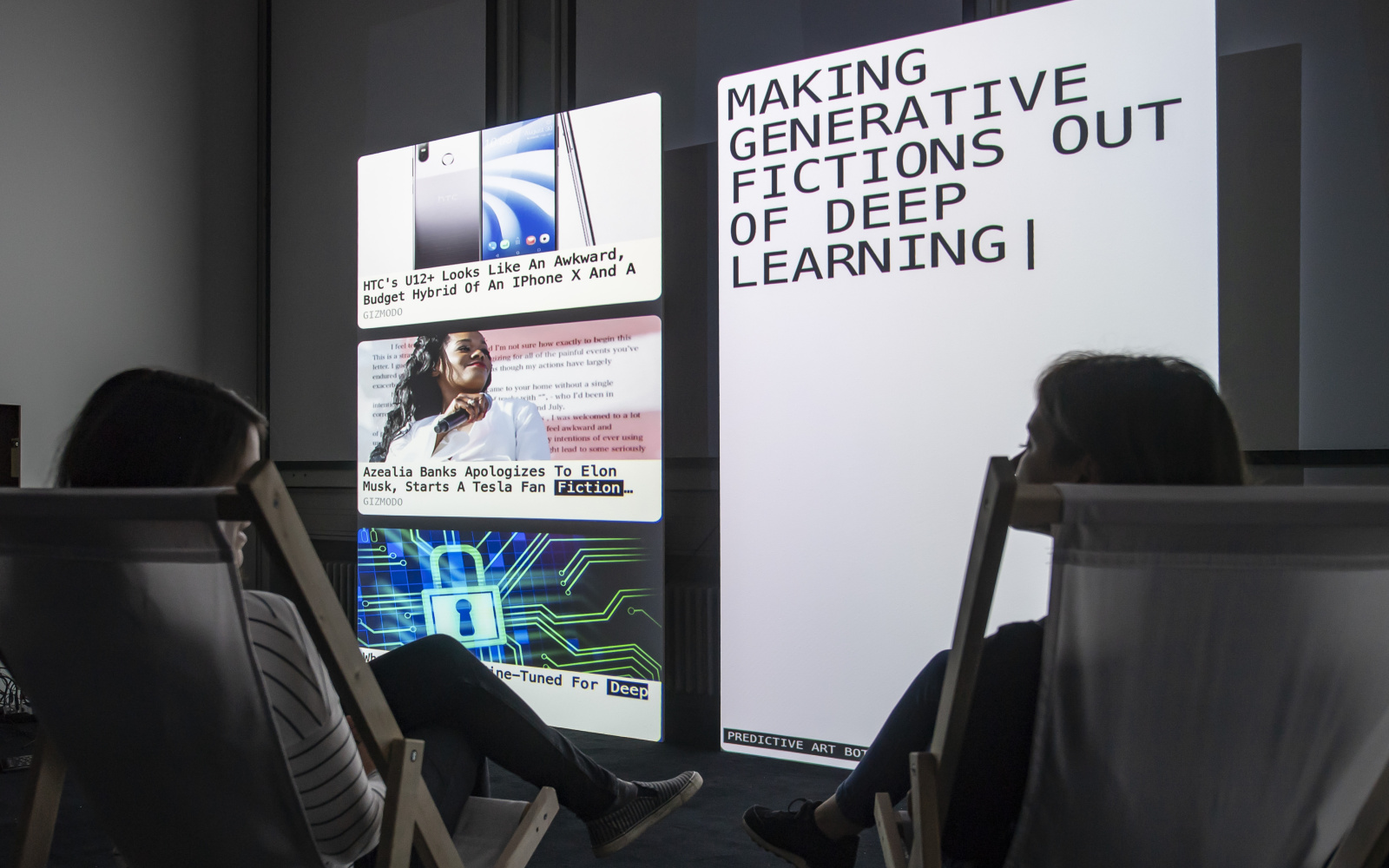 Zwei Personen sitzen in Liegestühlen vor zwei großen Bildschirmen. Auf dem rechten Bildschirm steht "Making generative fictions out of deep learning"
