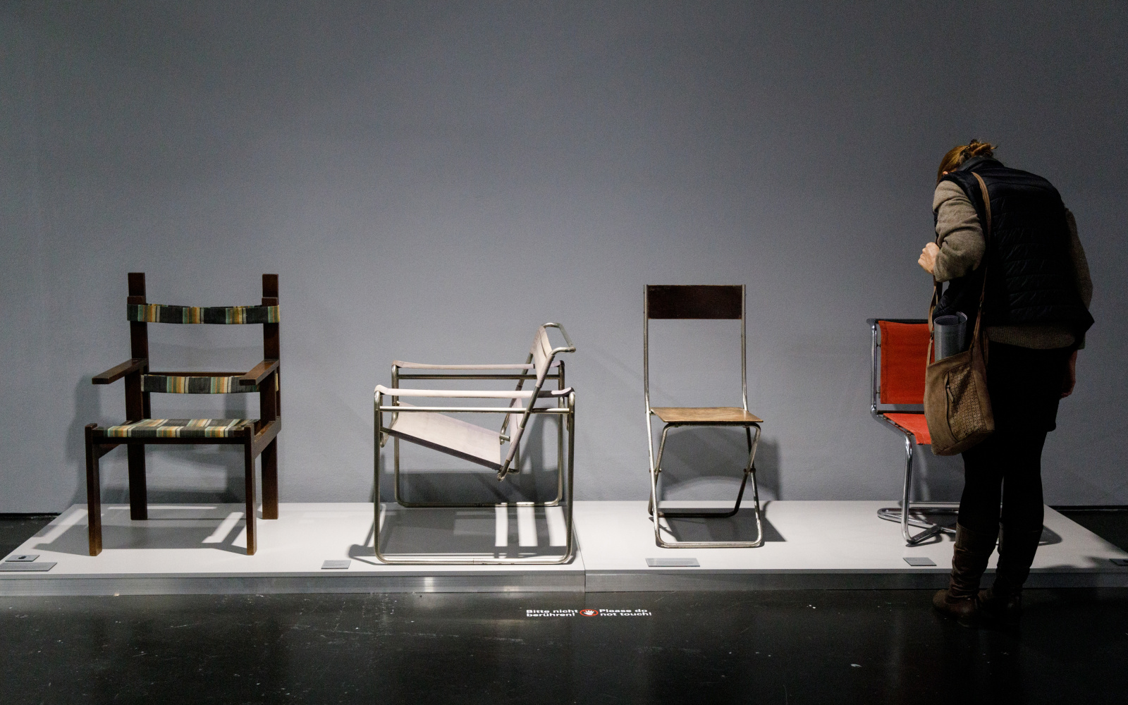Exhibition view »The Whole World a Bauhaus», Woman watching chairs of the Bauhaus-Collection