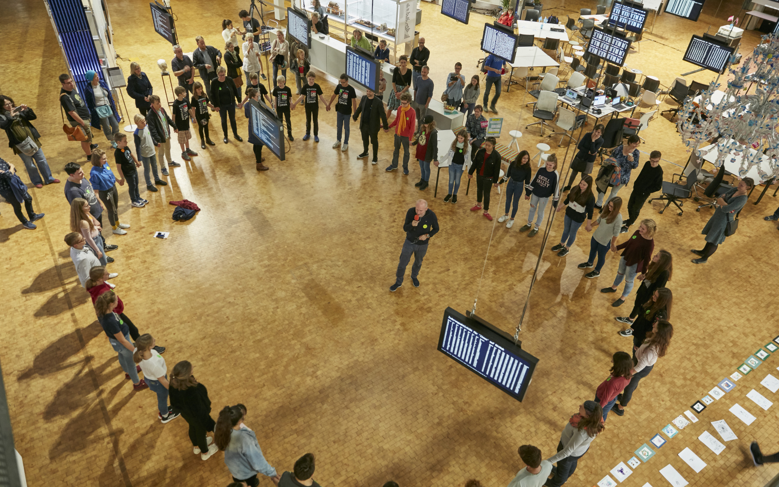 In the OpenHUB, several young people stand in a circle around a man who explains something to them.