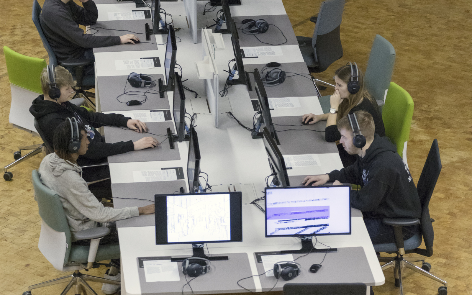 Mehrere Menschen sitzen an einem der Arbeitsplätze in "Open Codes II" an Computern