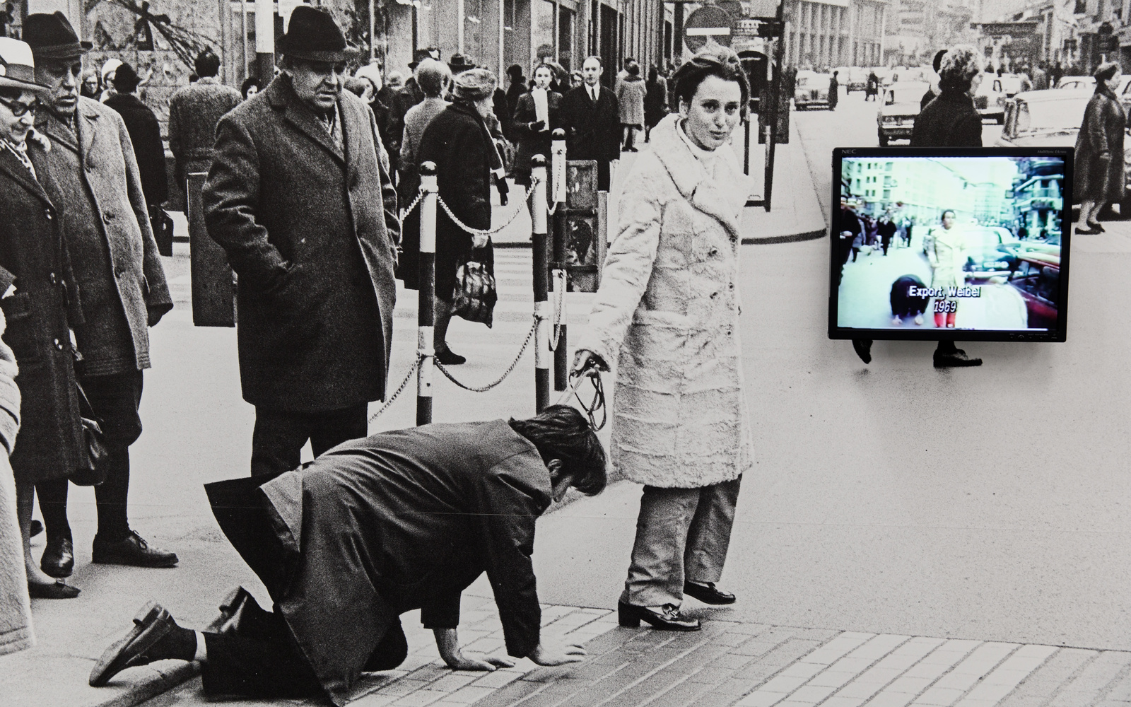 A black and white photo: It shows Valie Export leading Peter Weibel on a leash through a pedestrian zone.