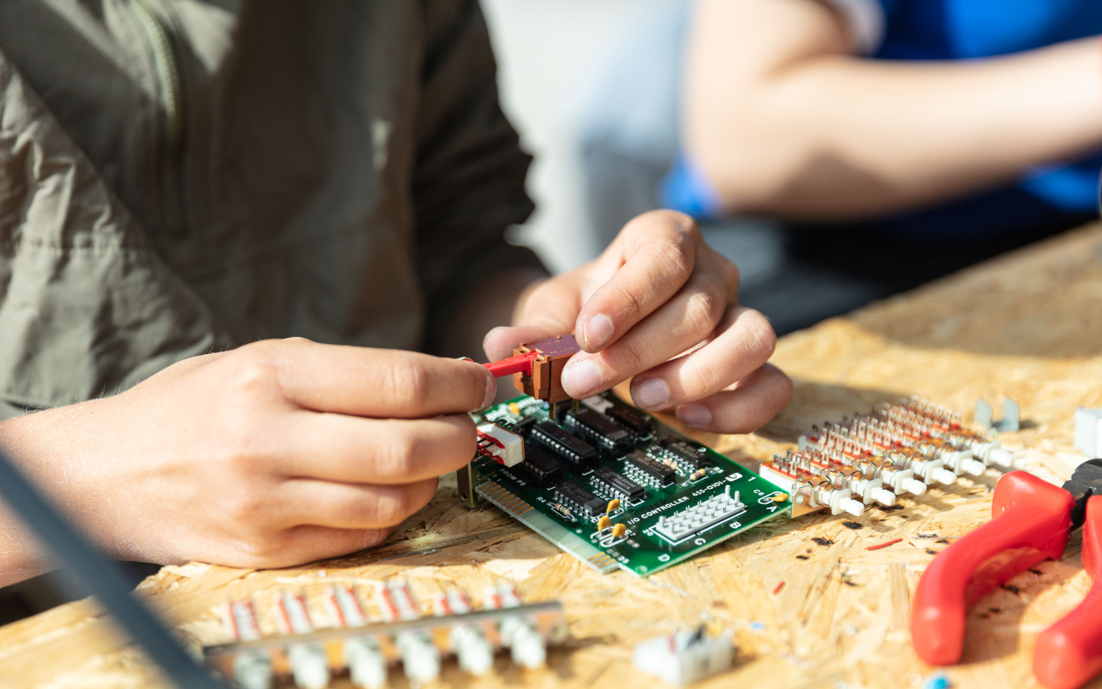 Two hands of a pupil can be seen soldering the components together during an event of the cultural academy.