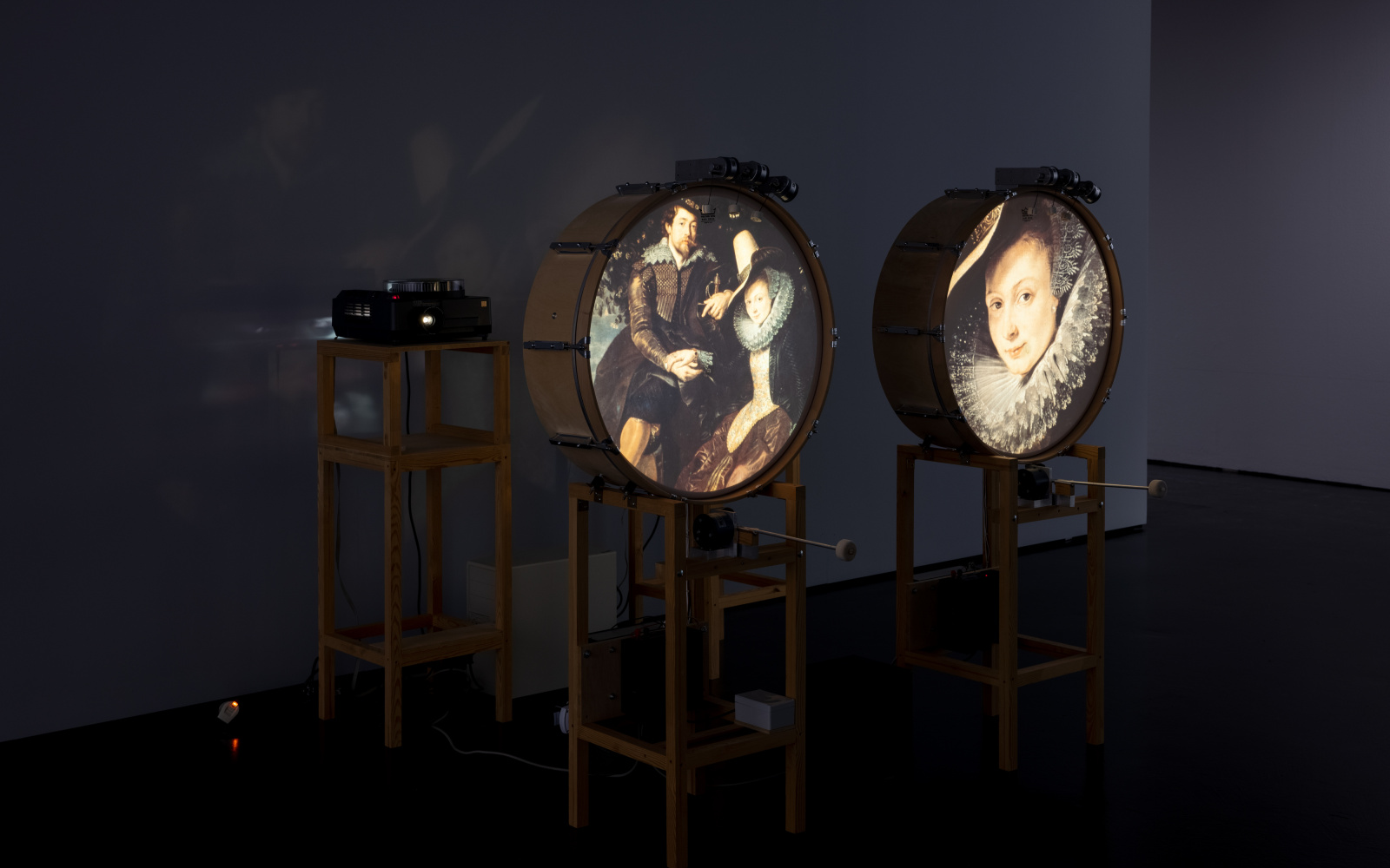 You can see two standing drums, each of which shows a picture on the round surface. On the left an ancient married couple and on the right the portrait of a woman. 
