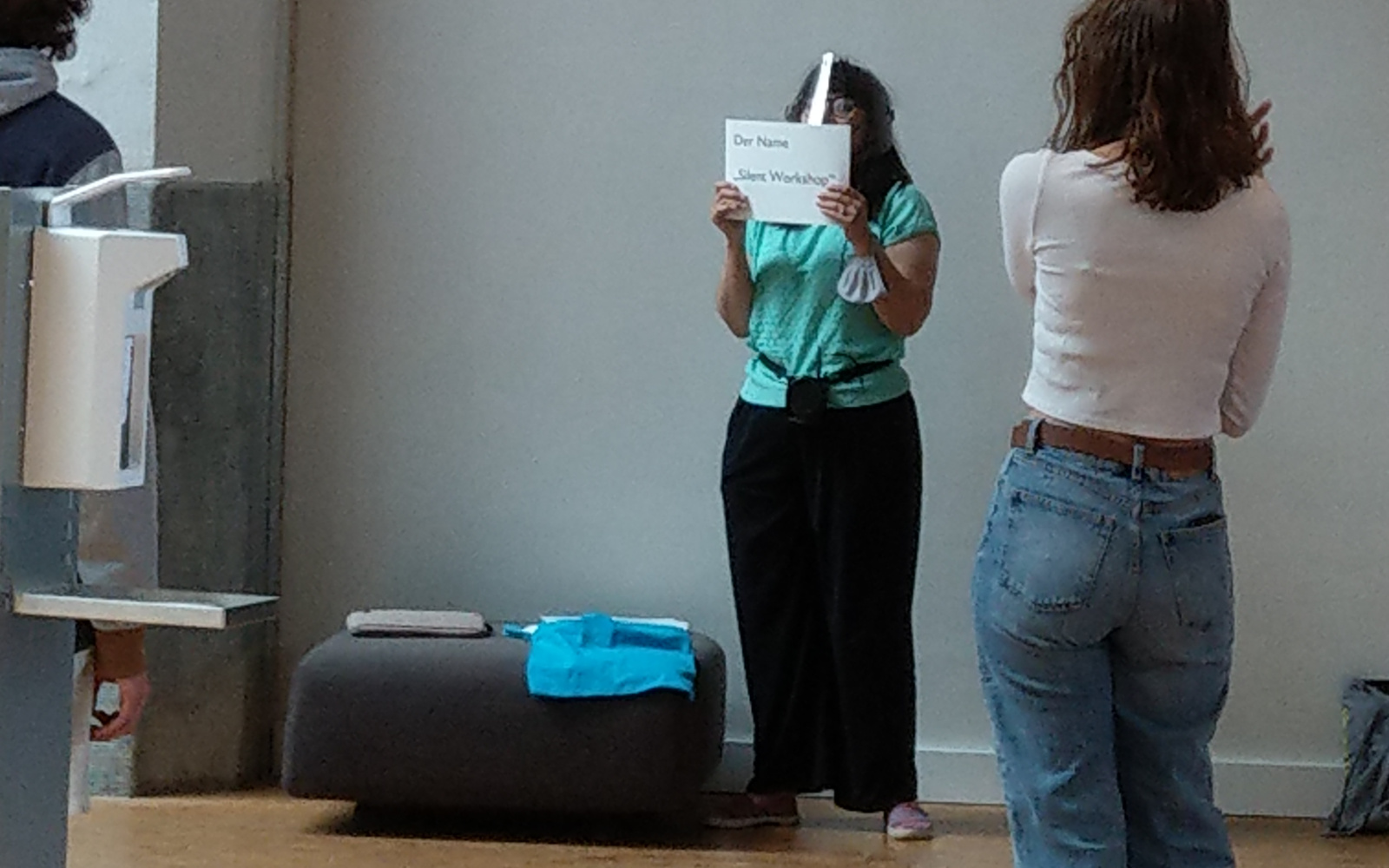 Carmen Beckenbach holds a sign in front of her face announcing the Silent Action workshop.