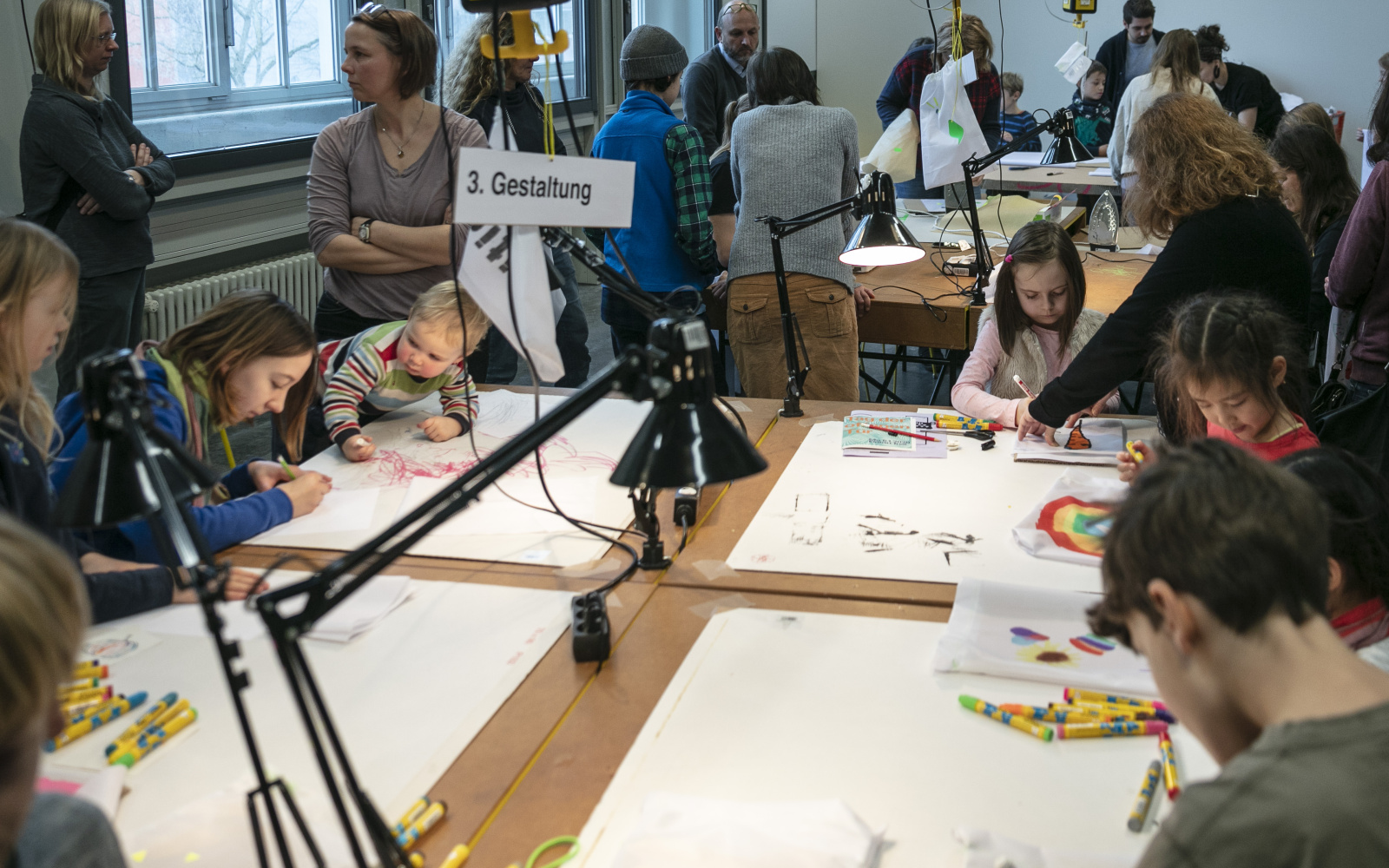 Viele Kinder malen am Tisch bei einem Workshop.