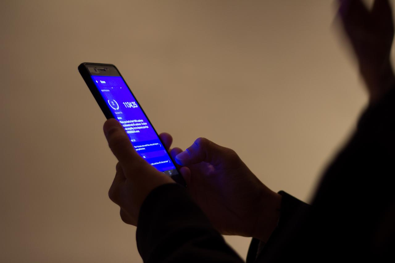 Hände bedienen ein Handy mit einem blauen Bildschirm