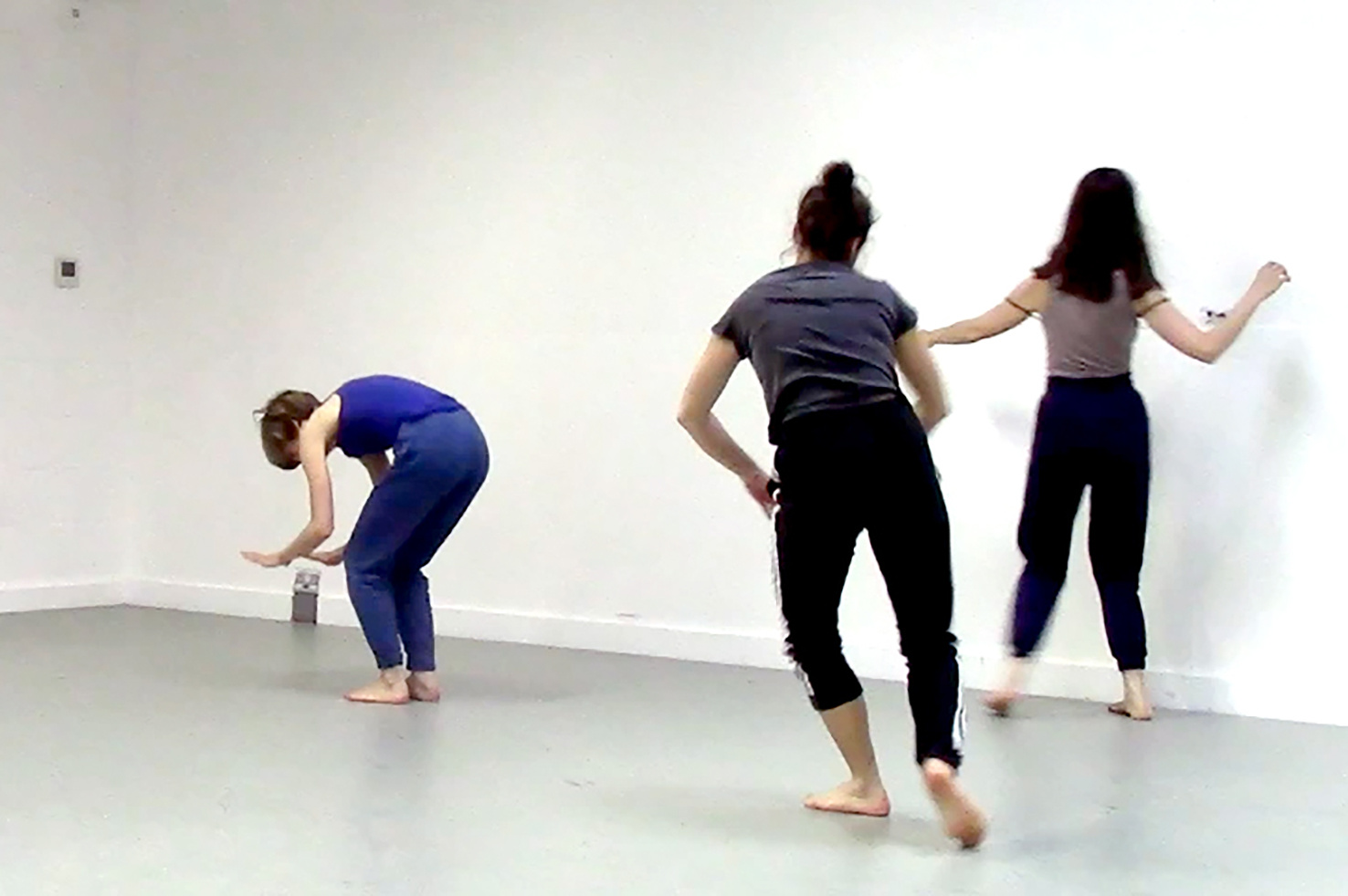 Three young women can be seen moving through the room in dancing movements.
