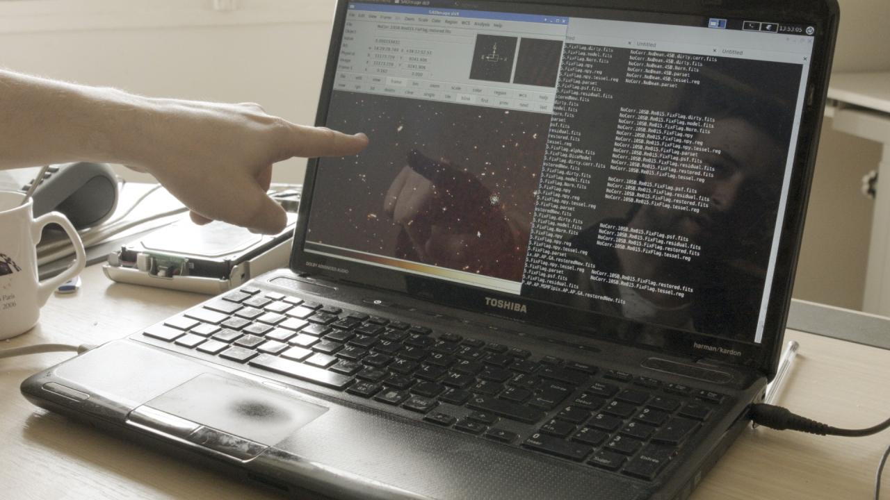 A male hand points to a computer screen