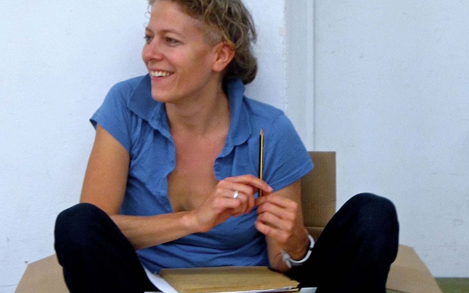  Anja Konjetzky sits casually in a cardboard box and holds a pencil in her hand.