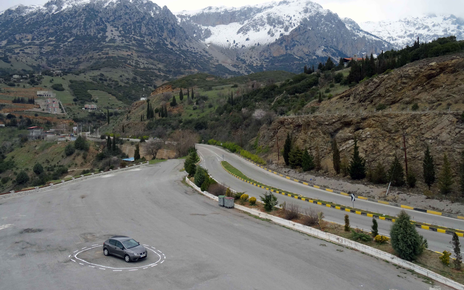 An auto driving car stands on an empty parking lot in a circle of a solid and a dashed white line.