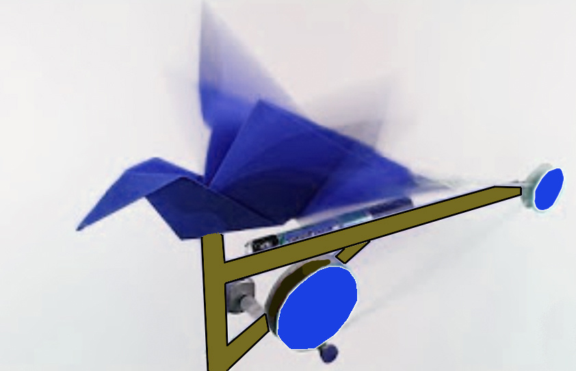 Ein aus blauem Papier gefalteter Origami-Vogel ist auf eine Unterkonstruktion mit Rädern geklebt. Außerdem ist eine Batterie an dem Objekt angeschlossen.