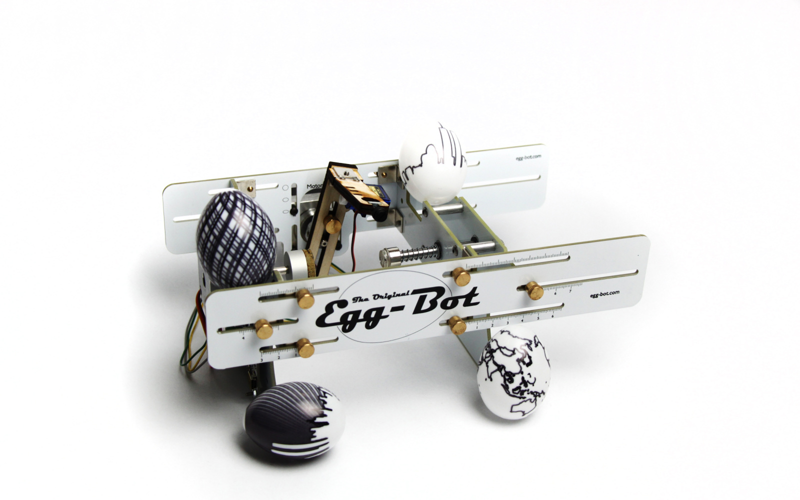The Egg-Bot with four different painted eggs in front of a white background