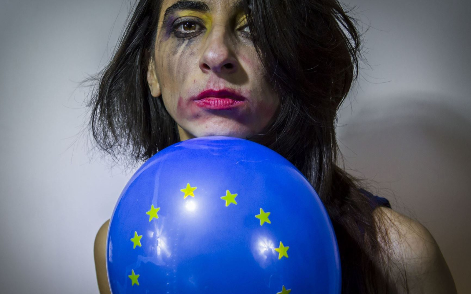 Gesicht einer Frau mit verwischtem Make-Up und Europa-Luftballon