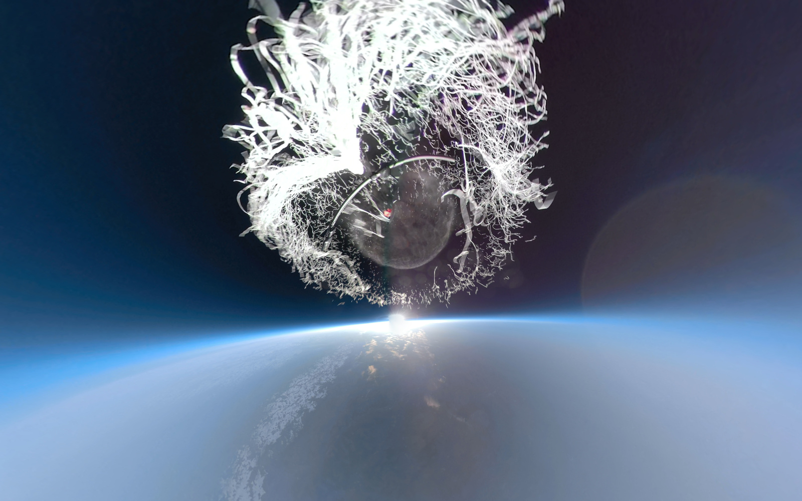 Ballonexplosion im Weltall über der Erde. Der Ballon zerfasert kugelförmig.