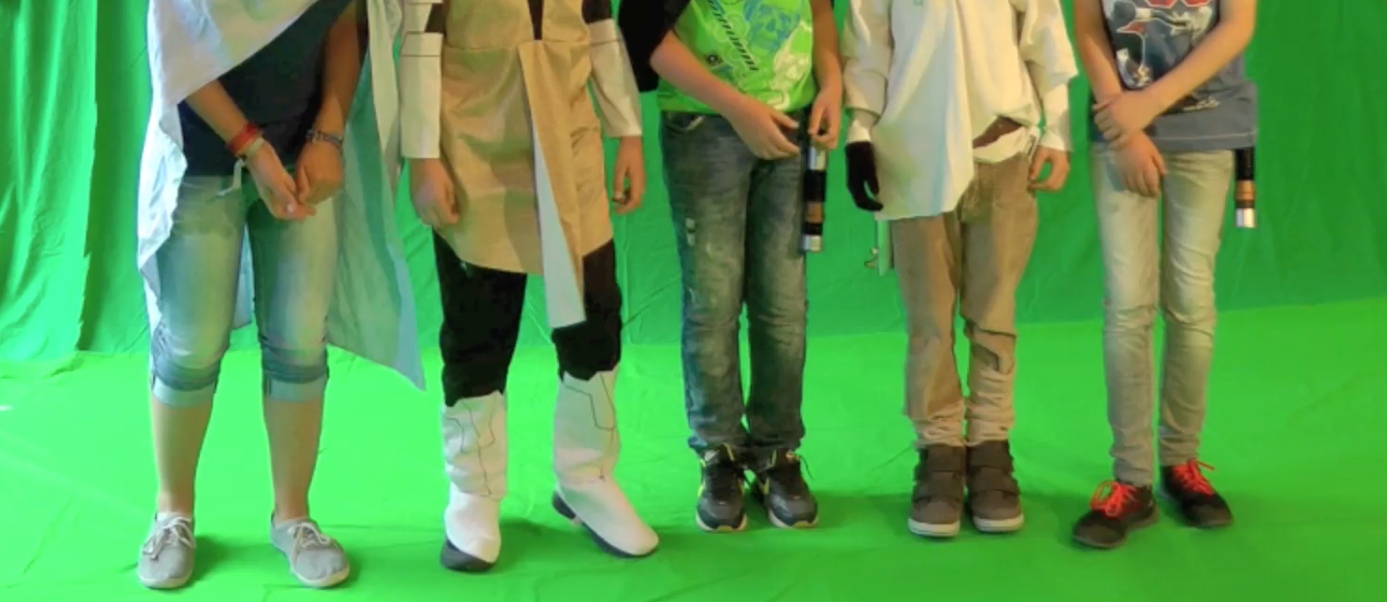 Fünf Kinder stehen nebeneinander vor einem Greenscreen - man kann nur ihre Beine sehen.