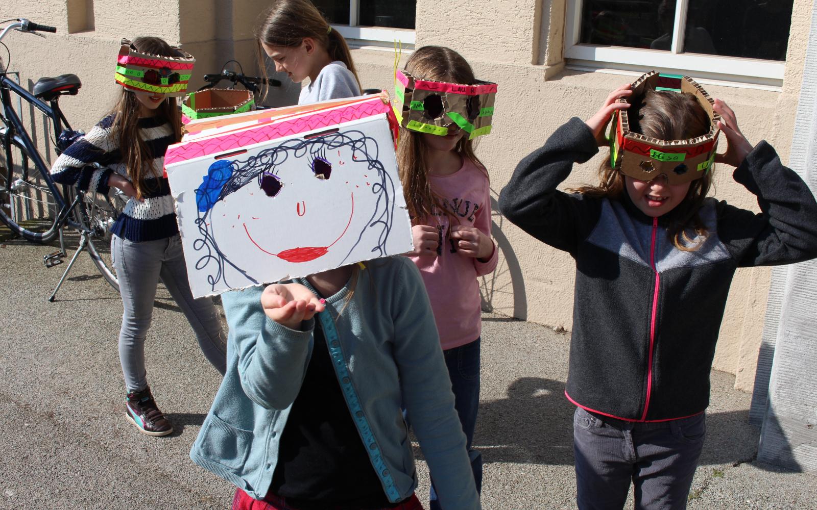 Eine Gruppe Mädchen, die sich aus alltäglichen Gegenständen Masken gebastelt haben stehen vor dem Eingang zum ZKM Gebäude.