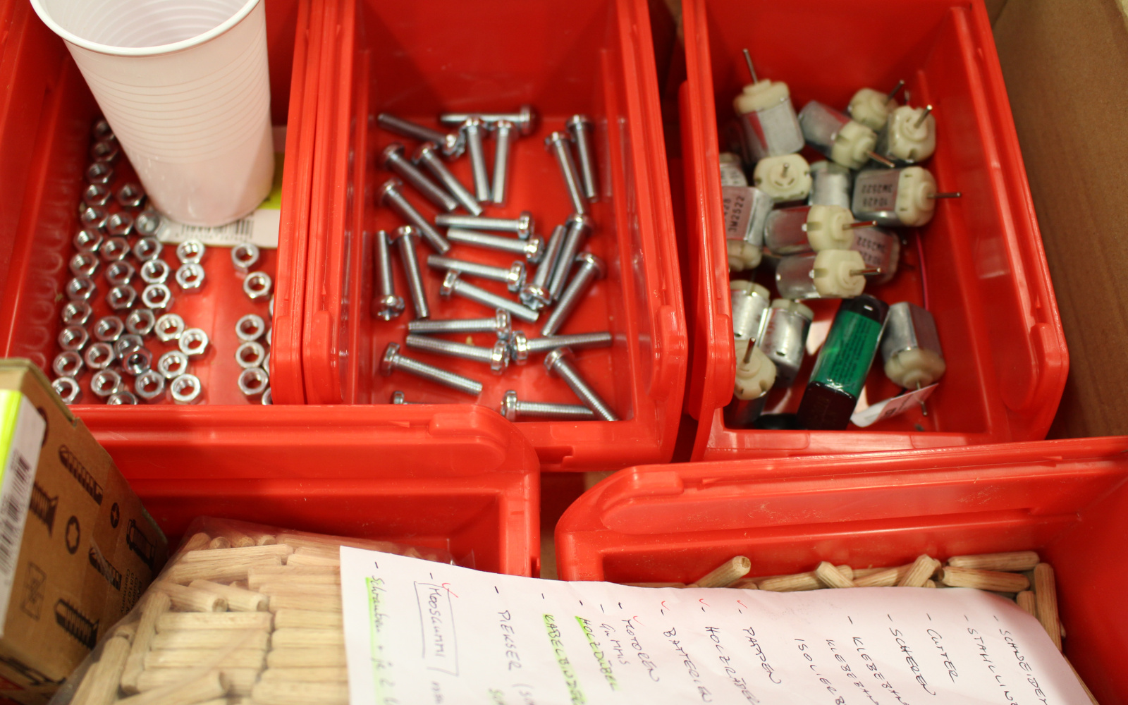 Some red boxes for crafting equipment in which are different screws, nails or little motors.
