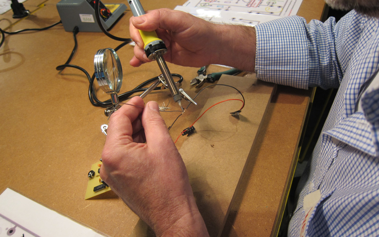A man is soldering two wires together.