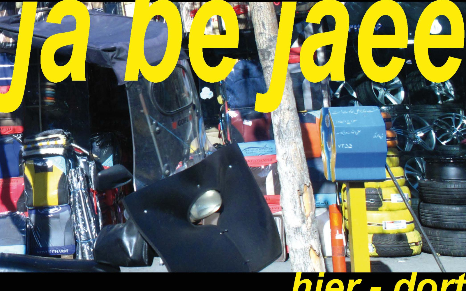 The photo shows car tires and scrap. The picture bears the inscription ja be jaee. here there. The writing is lemon yellow.