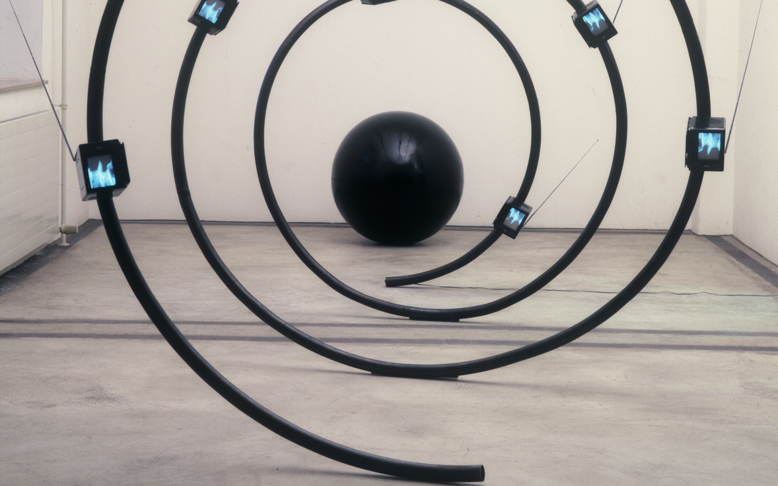 Eine Skulptur aus einer schwarzen Spirale mit kleinen Bildschirmen, die Arbeit heißt »The name« und stammt von Michael Bielicky.