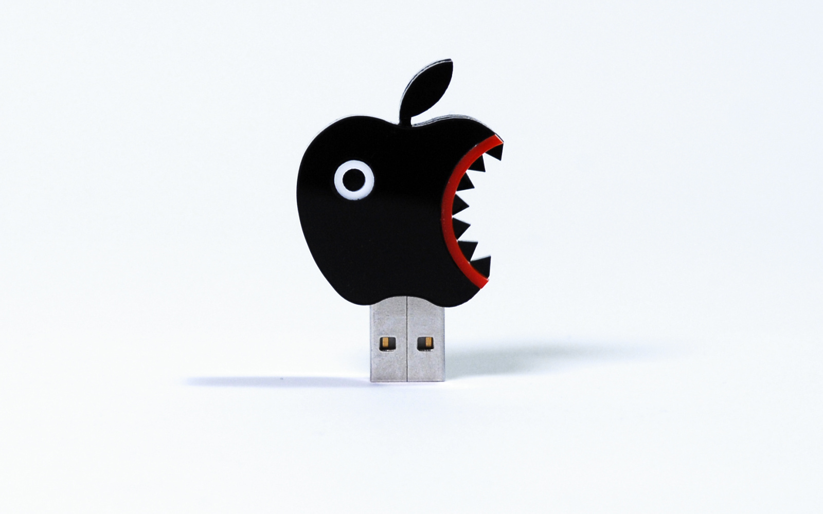 The photo shows a USB stick in the form of a black PacMan-like apple icon.