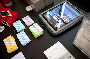 Numerous promotional materials at the stand of the ZKM. Colorful business cards and a tablet with a photo of the ZKM on it.