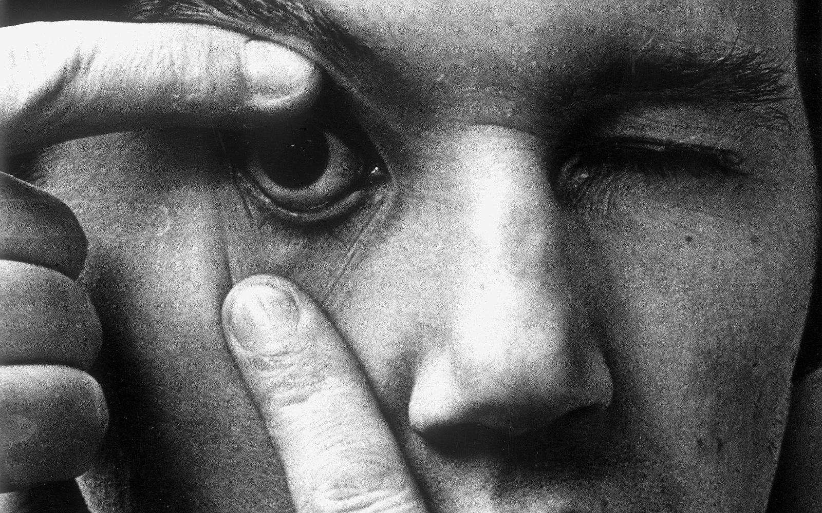 Die Portraitaufnahme zeigt Peter Weibel im Rahmen der Ausstellung »respektive Peter Weibel«. Auf dem Foto öffnet der Künstler sein rechtes Auge mit den Fingern.