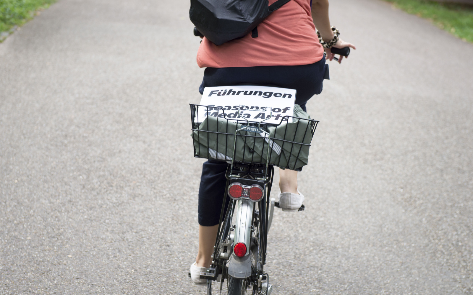 There's a white laminated sign in a bike basket that says »Guided Tours Seasons of Media Arts«.