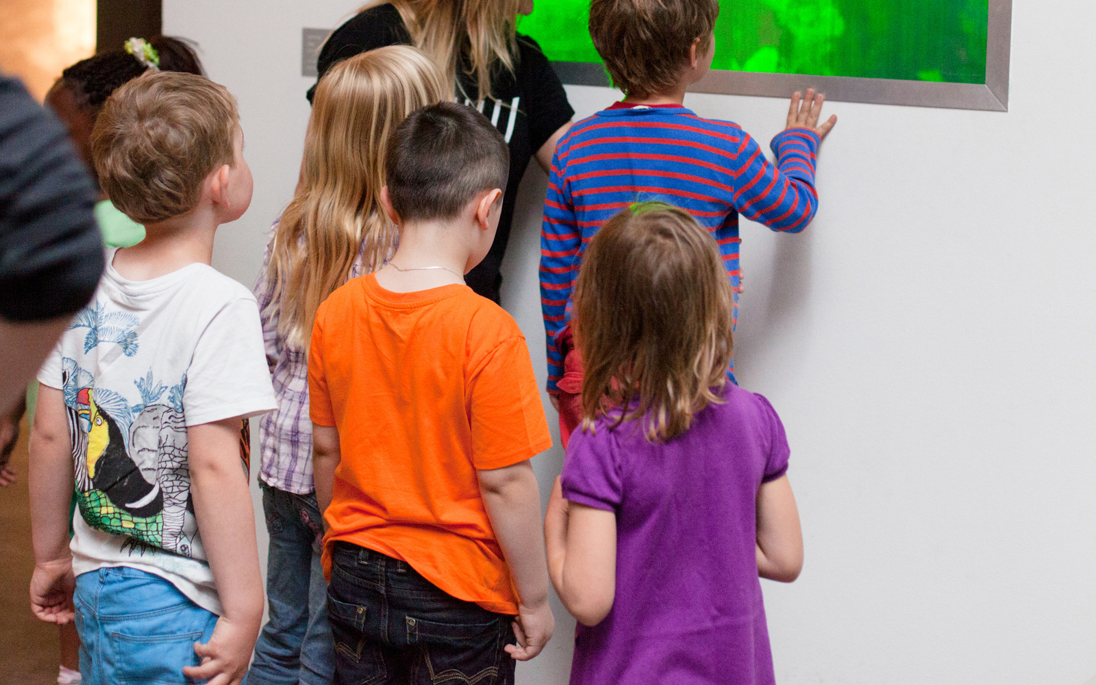 Eine Gruppe von Kindern betrachtet ein grün leuchtendes Bild.